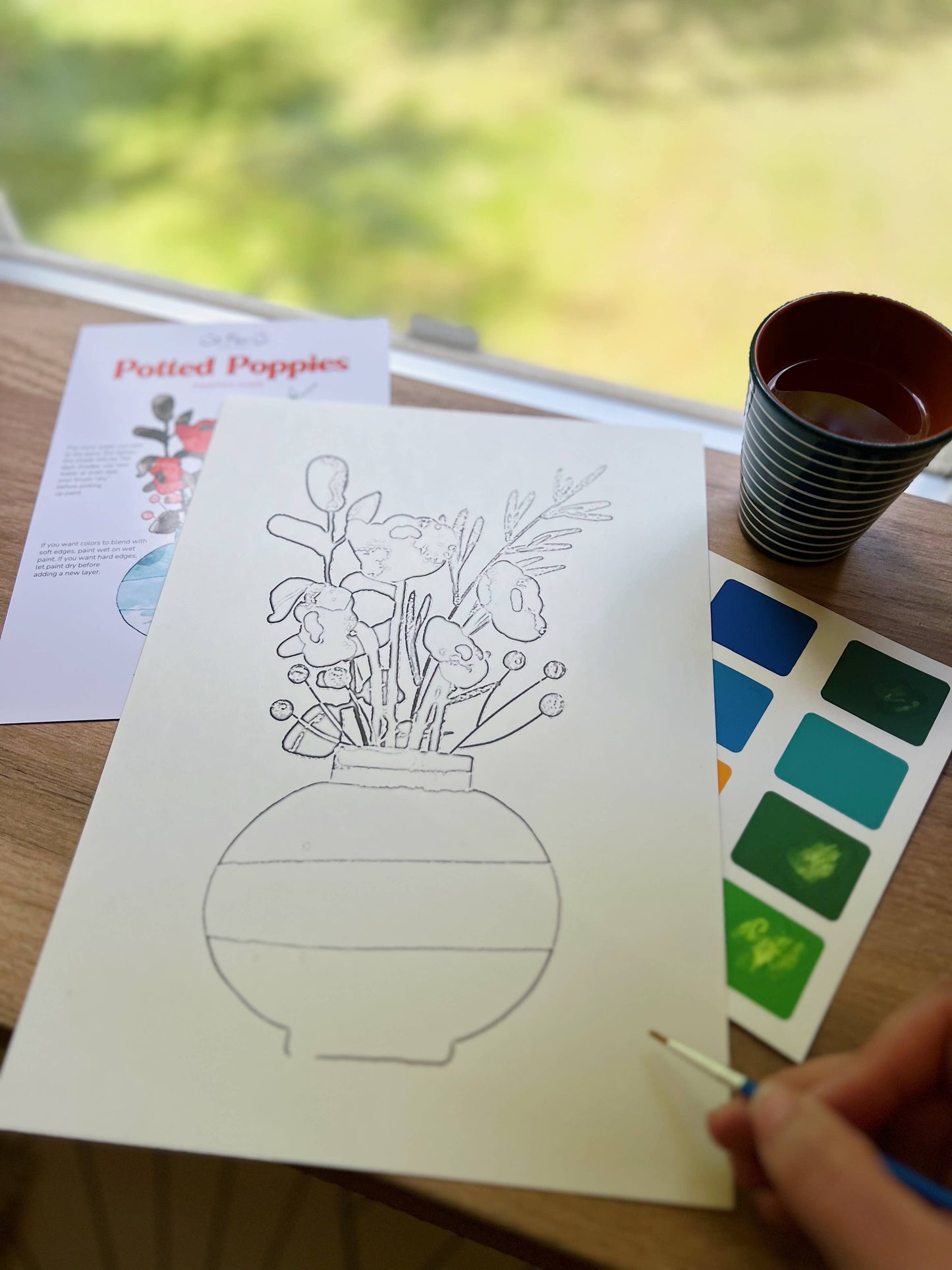 Coloring book page with a vase of flowers on a table with art supplies.