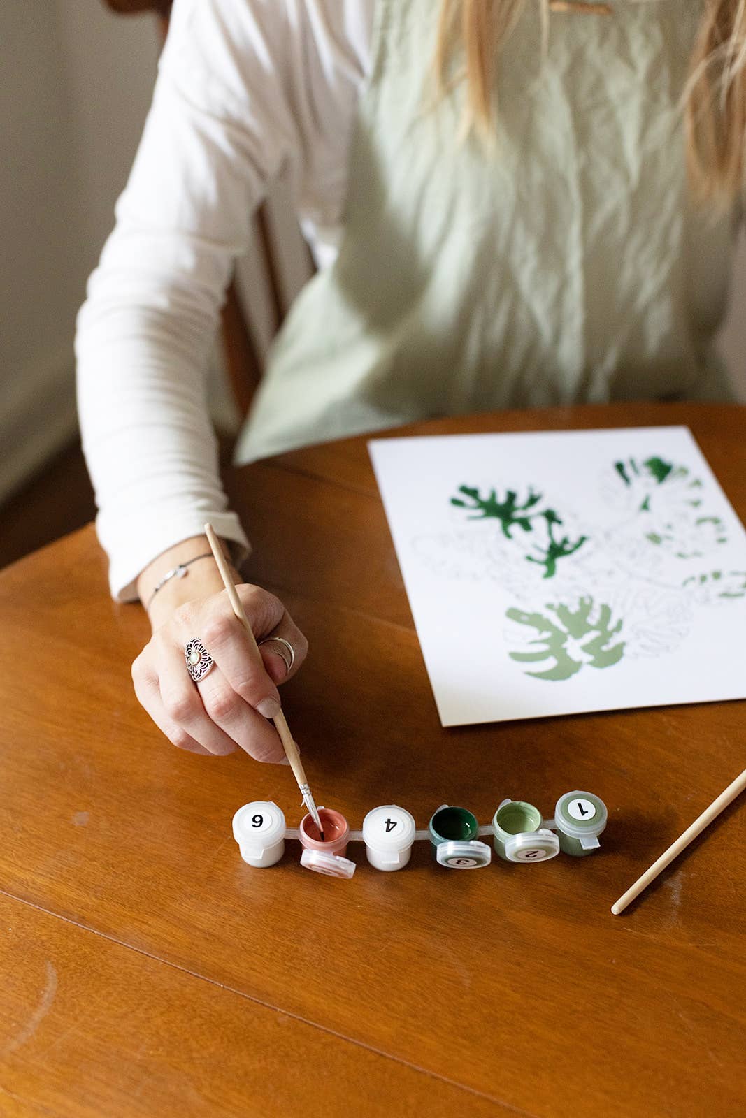 Person painting letters on small round canvases with a paintbrush.