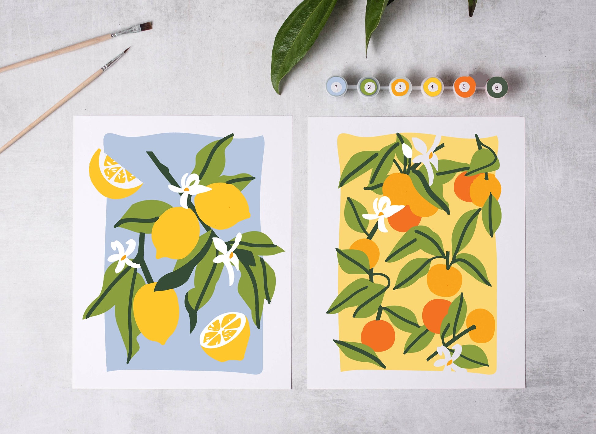 Two artistic illustrations of lemons and oranges on a textured surface with paintbrushes and color swatches.
