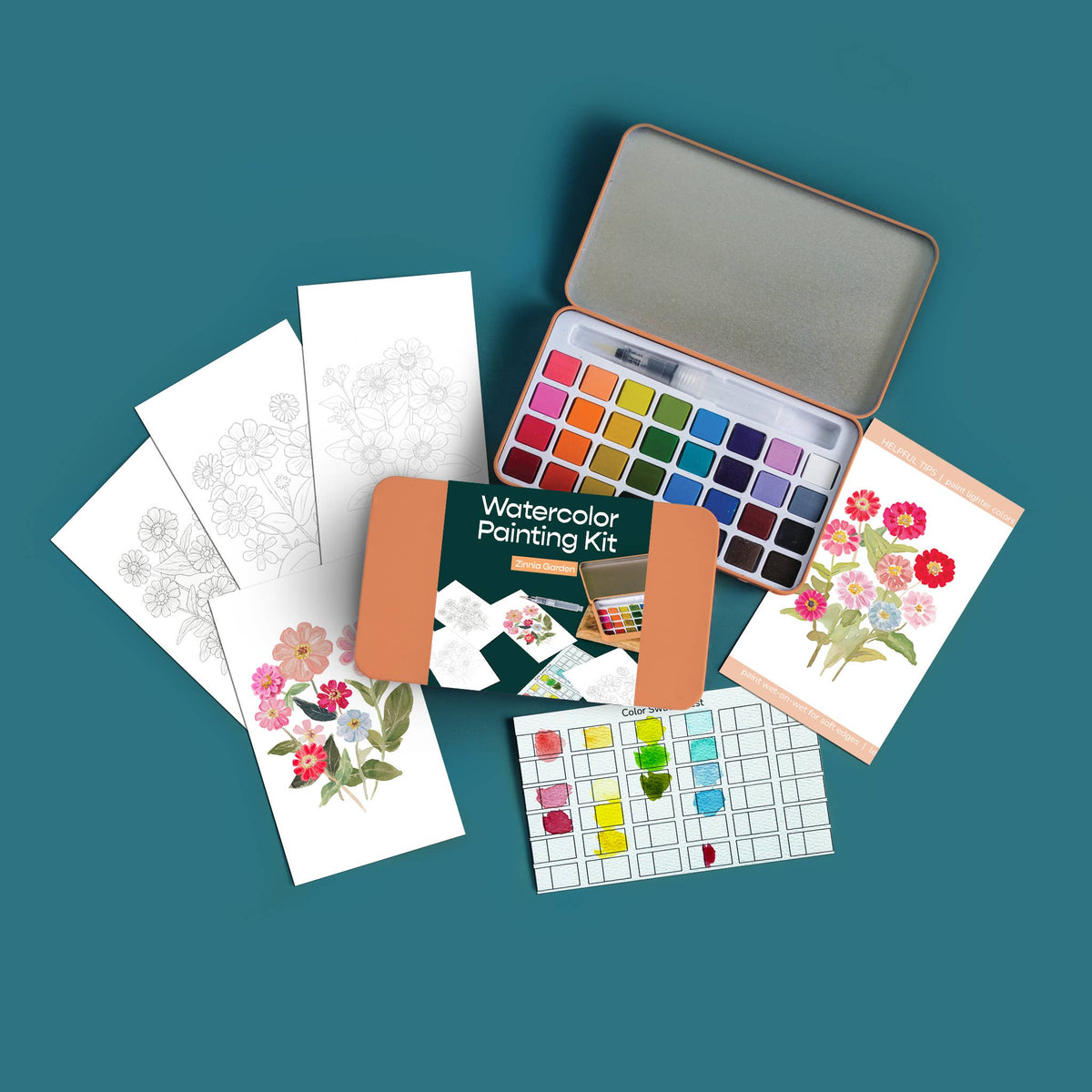 Watercolor painting kit with paint swatches, cards, and a tin on a teal background