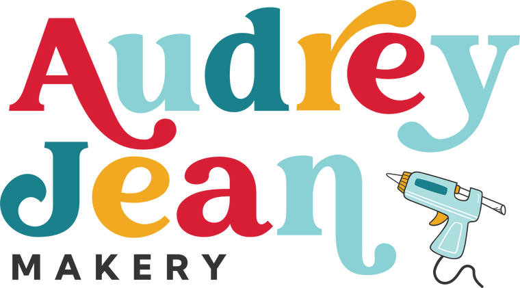 Colorful logo of Audrey Jean Makery with a glue gun icon on a white background