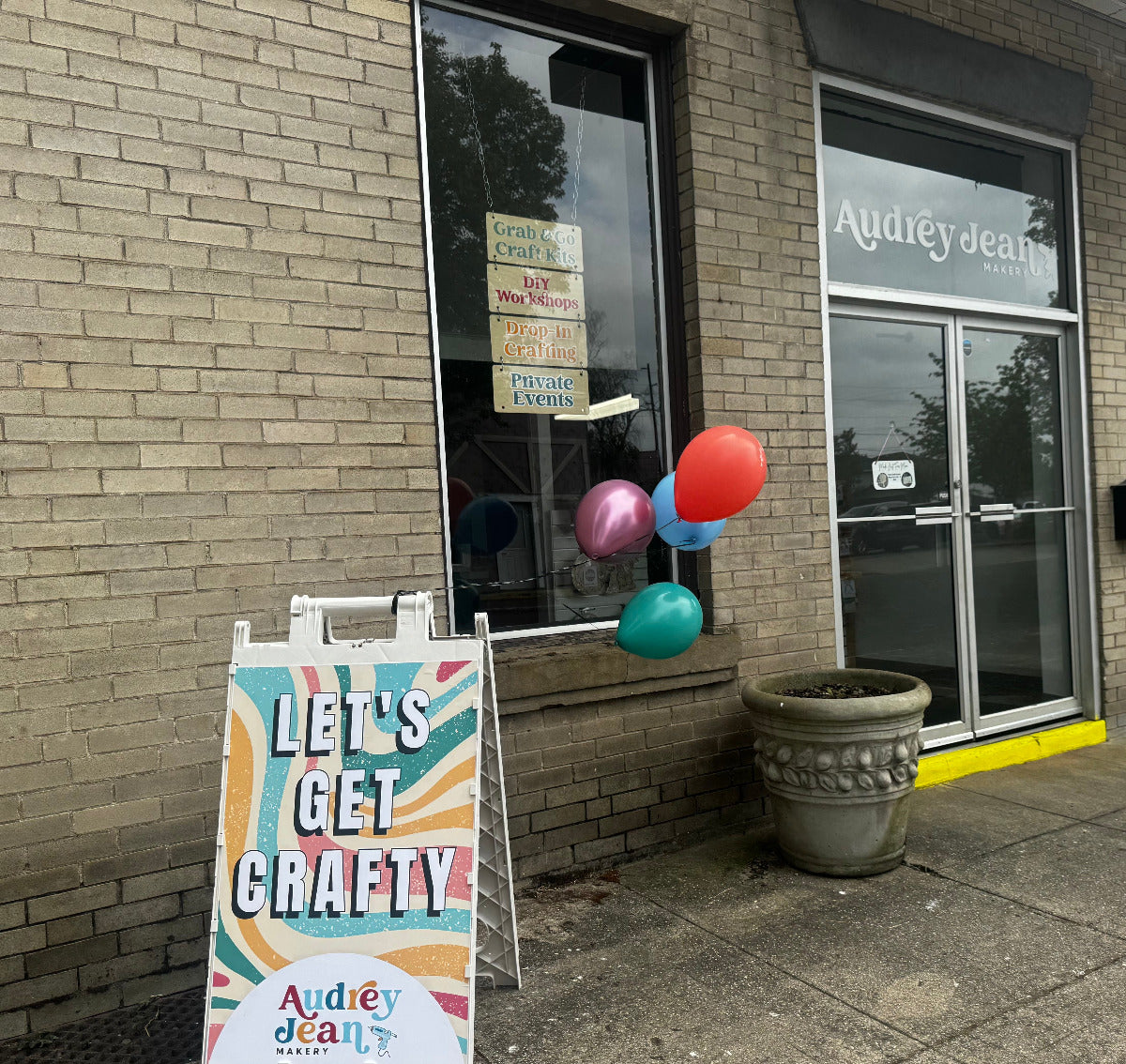 Storefront with a 'Let's Get Crafty' sign and balloons outside.