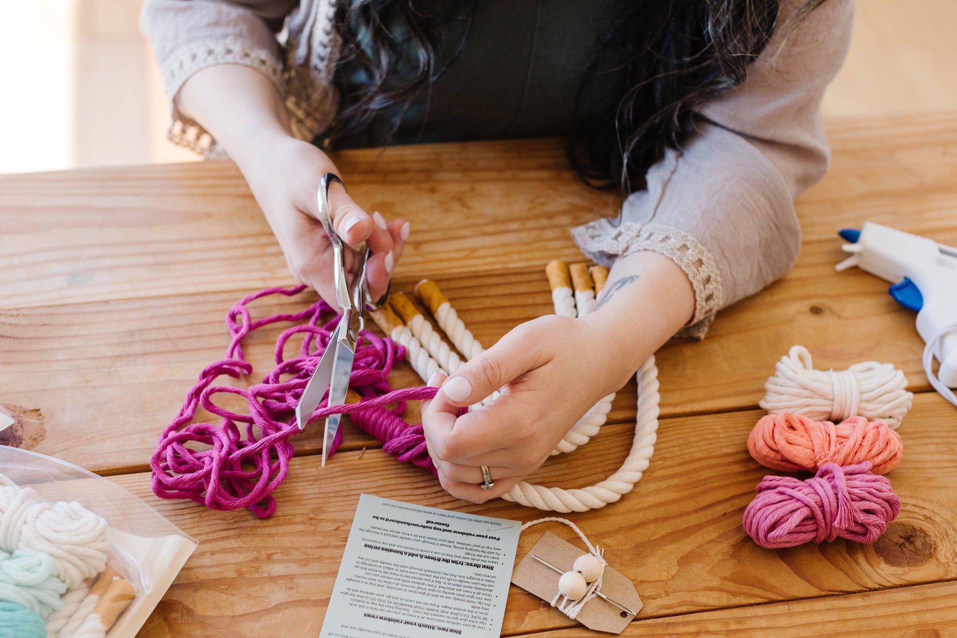 Person crafting with yarn and scissors on a wooden table